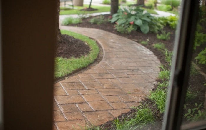A curved brick pathway winds through a landscaped garden.