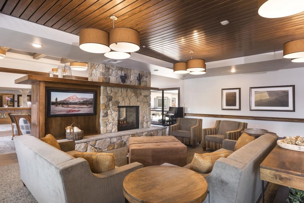 A cozy and modern living room featuring a stone fireplace, comfortable seating, and a wooden ceiling.