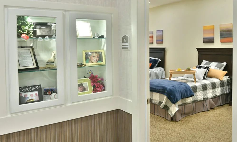 A cozy bedroom featuring a display cabinet with personal items and photographs.