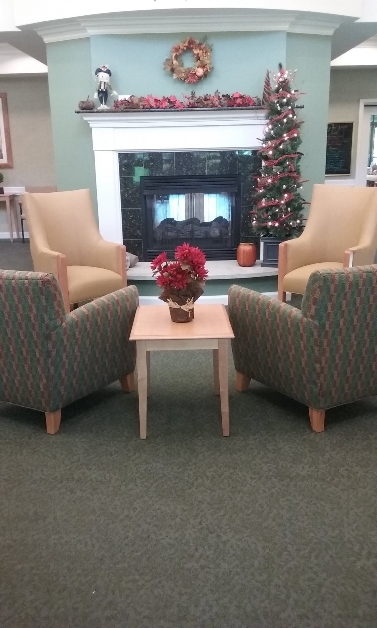 A cozy seating area with armchairs and a coffee table near a fireplace, decorated with a Christmas tree.