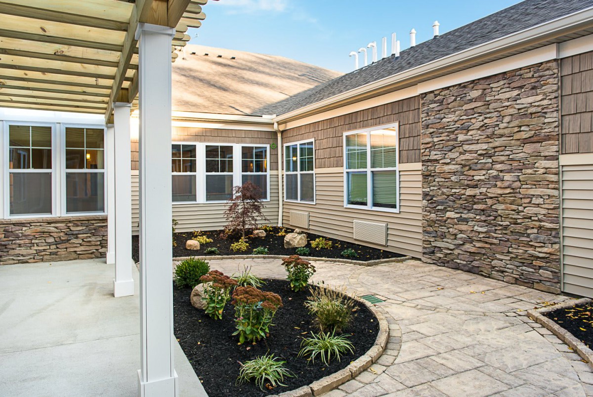 A beautifully landscaped patio with plants and a stone wall.