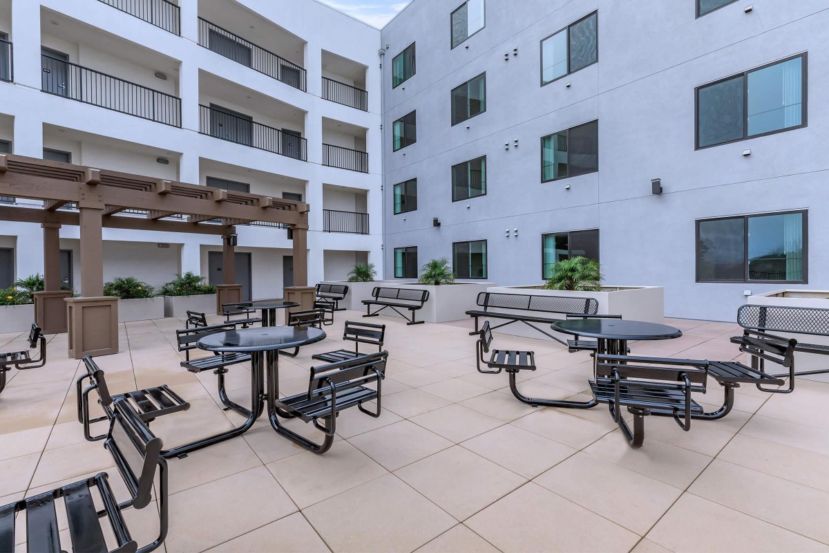 Modern apartment courtyard with tables and chairs for outdoor seating.
