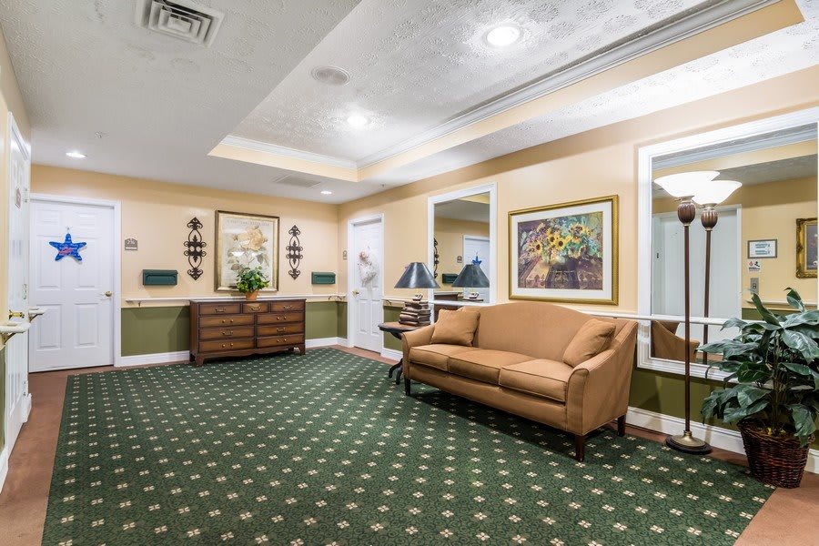 A well-decorated lobby with a sofa, patterned carpet, and framed artwork.