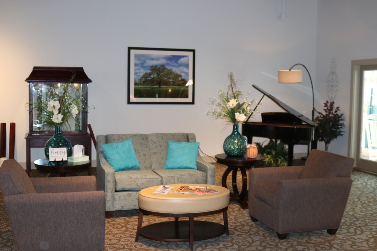 A cozy living room with a sofa, armchairs, and a piano, accented by decorative elements and artwork.