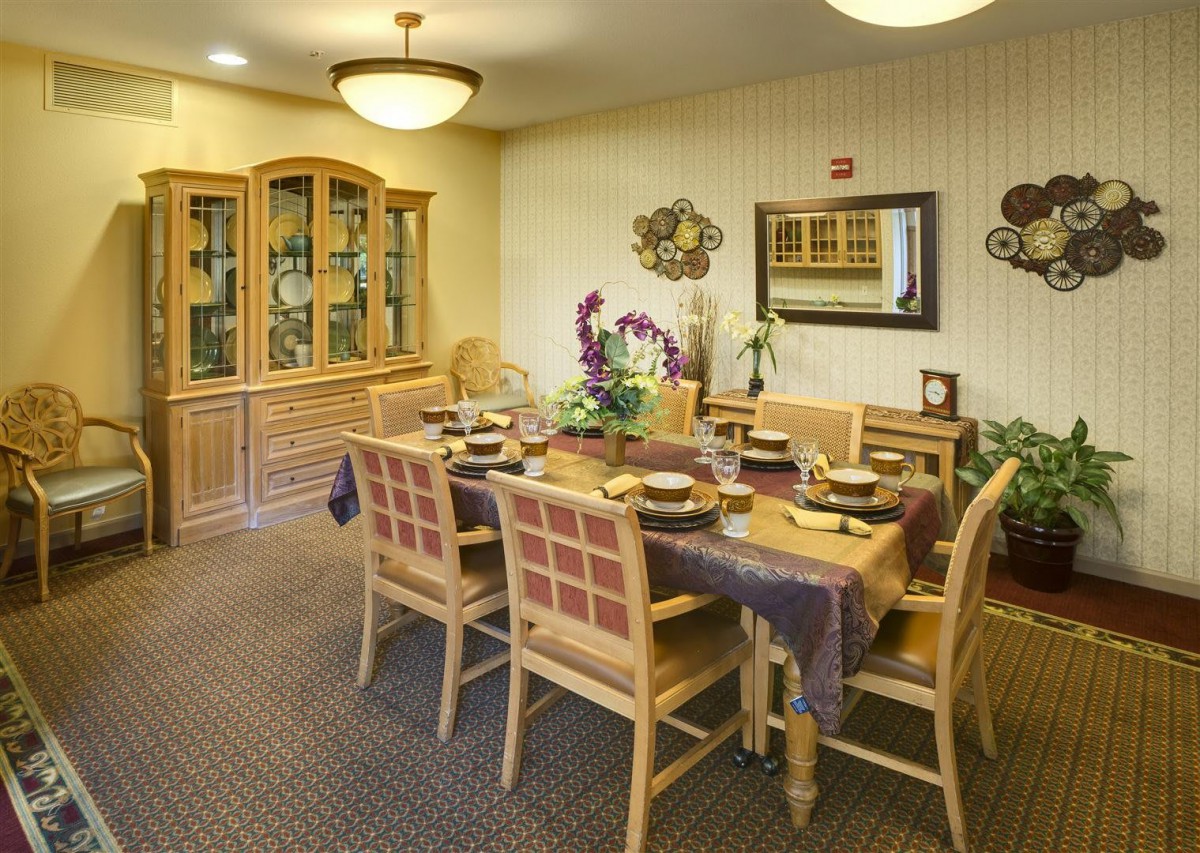 A warm and inviting dining room with a neatly set table and wooden furniture.