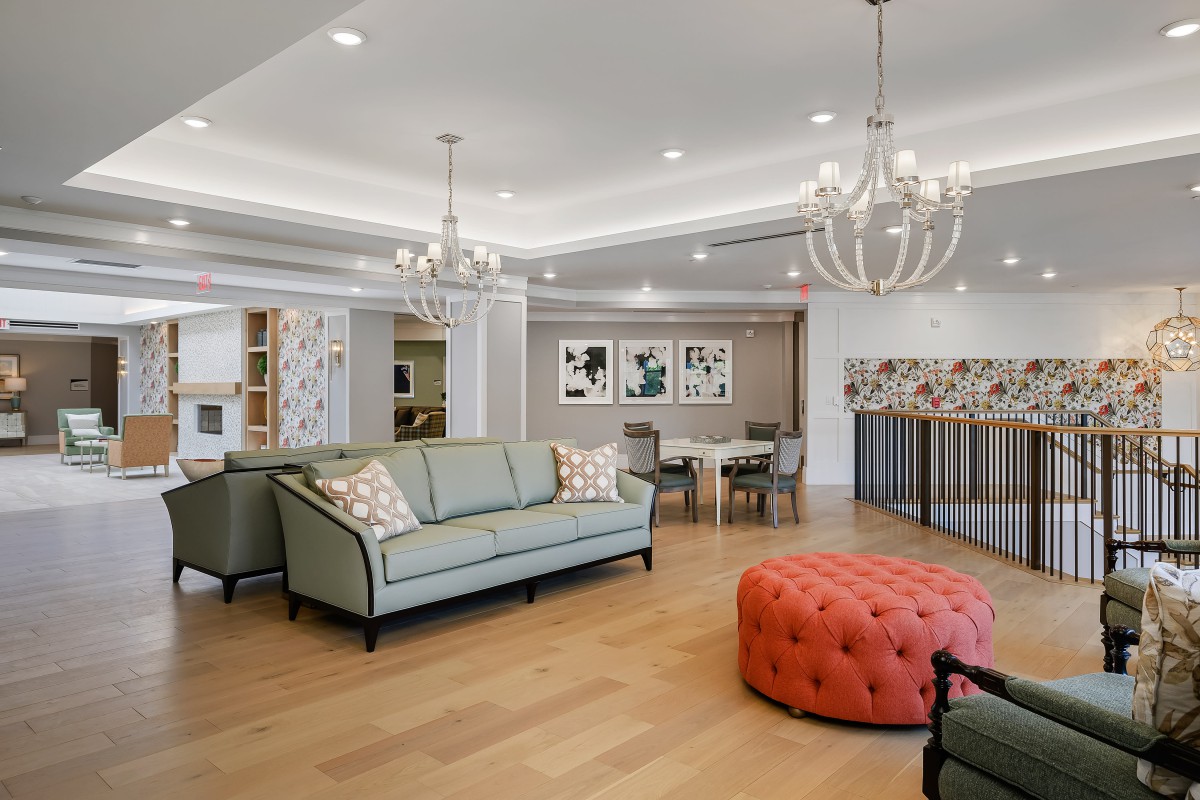 A modern living room featuring a stylish sofa set, chandeliers, and vibrant artwork on the walls.