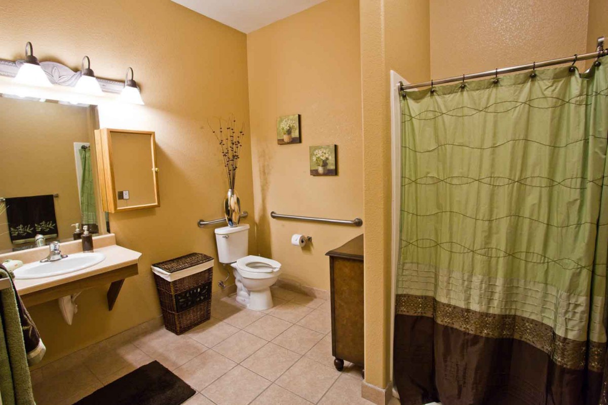 A well-organized bathroom with tan walls and a green shower curtain.