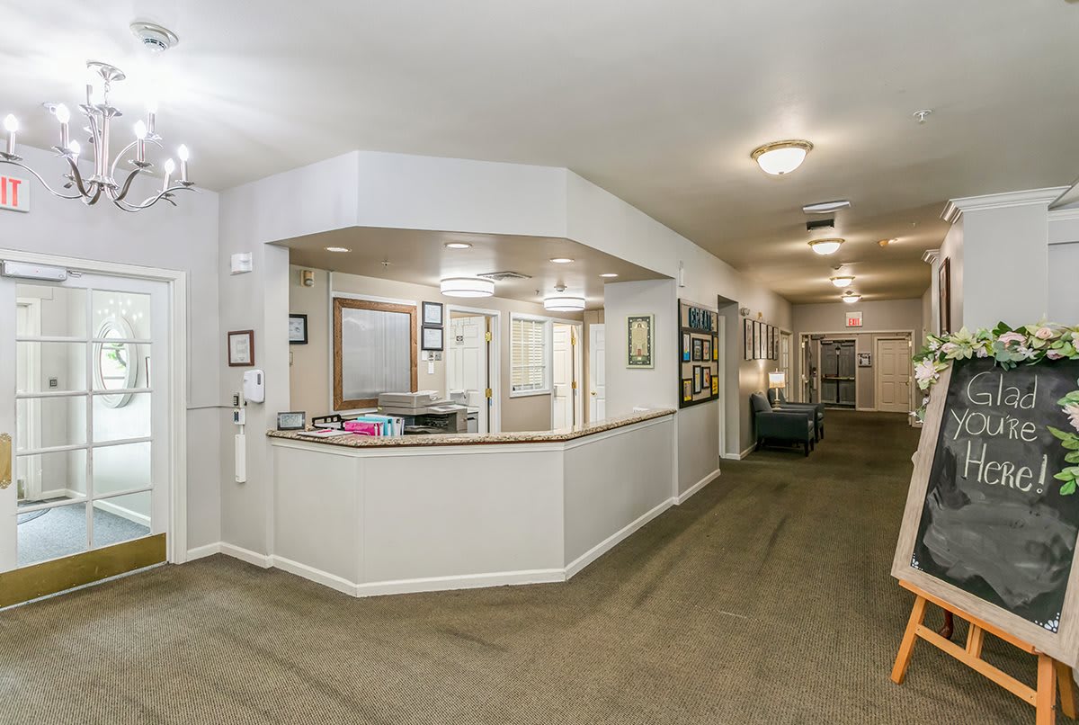 A spacious reception area in an office setting with a long hallway and framed artwork on the walls.