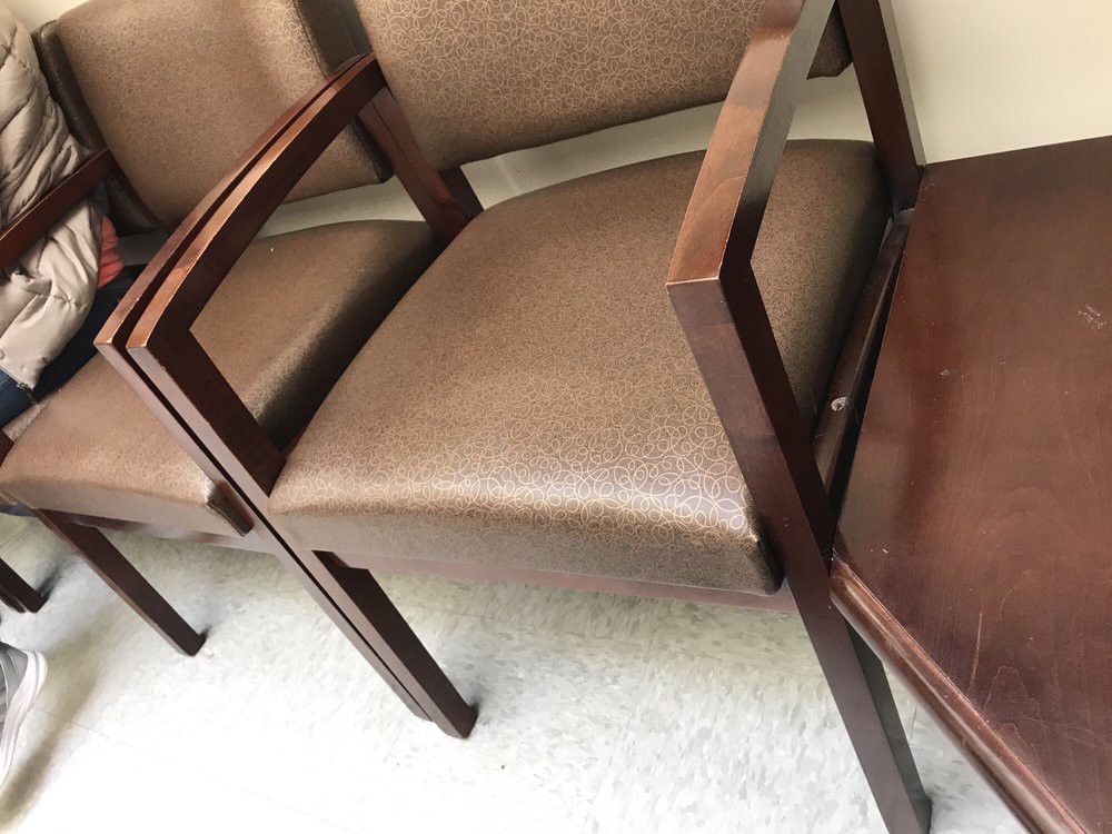 A row of upholstered chairs with wooden arms in a waiting room setting.