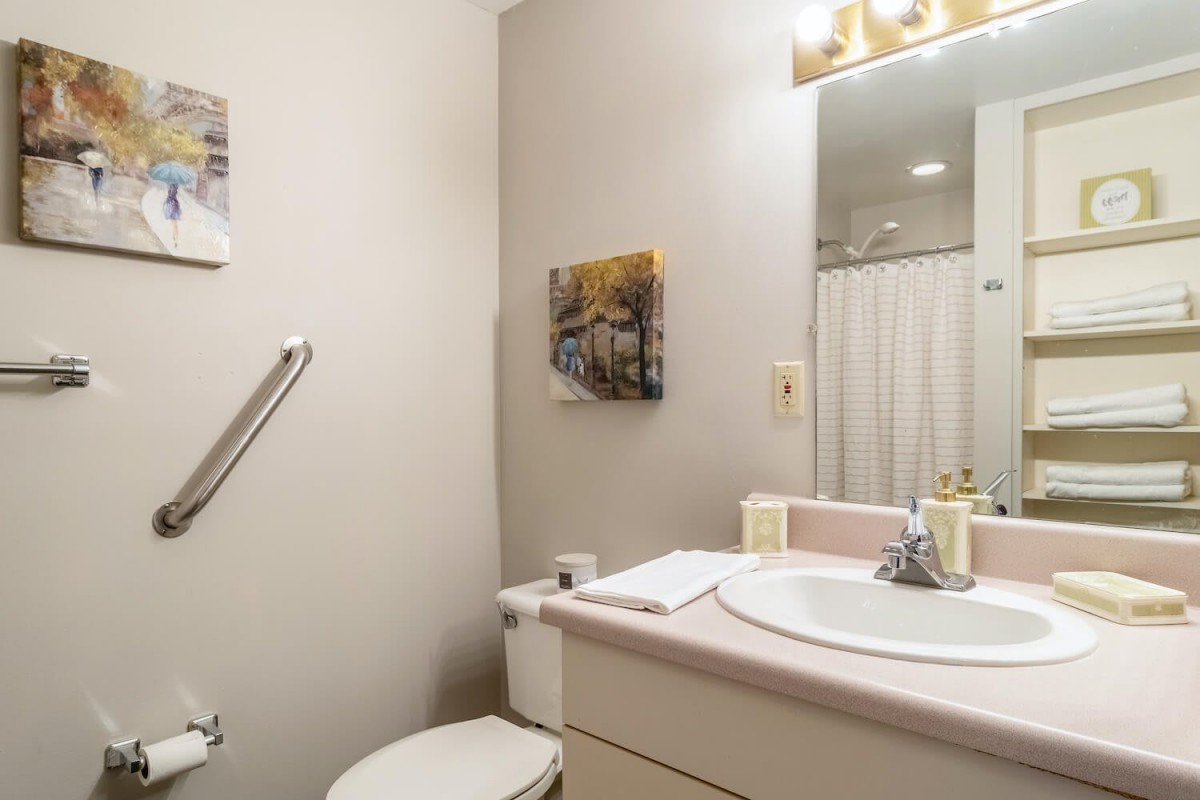 A clean and simple bathroom with a sink, toilet, mirror, and towel rack.