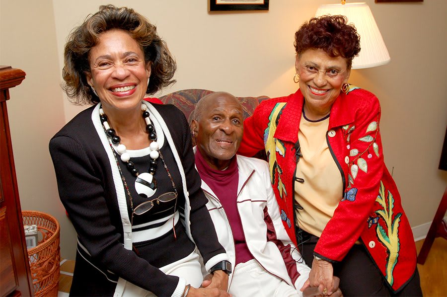 Three people sitting together on a couch, smiling and appearing happy.