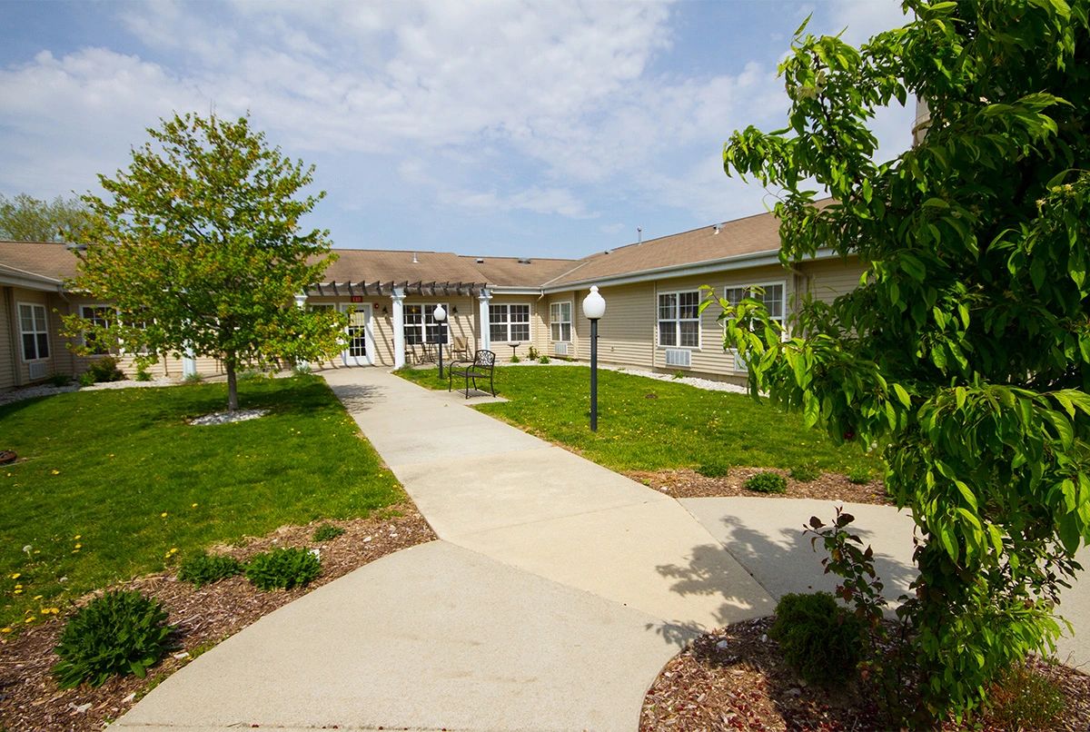 A scenic view of a residential building with a paved walkway and surrounding greenery.