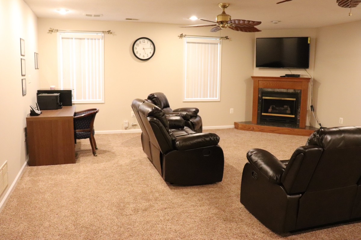 A cozy living room with leather seating, a fireplace, and a television.
