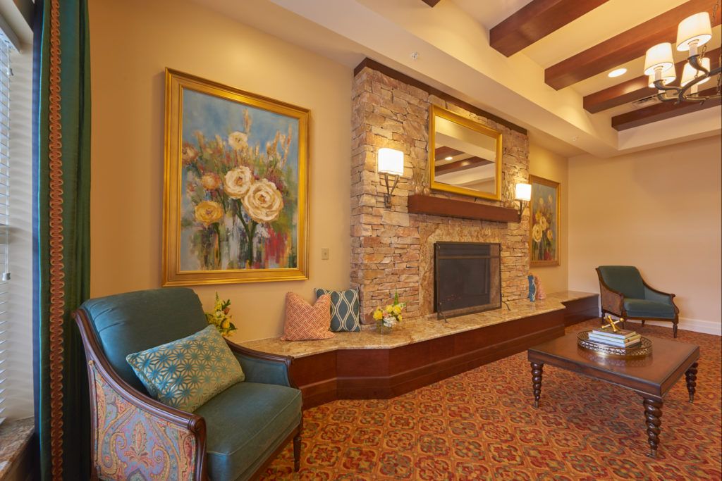 A cozy living room with a stone fireplace, decorated with elegant paintings and warm lighting.