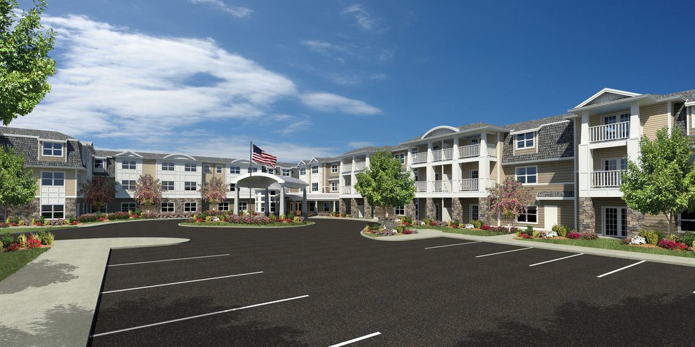 A modern apartment complex with a large parking lot and an American flag flying at the entrance.