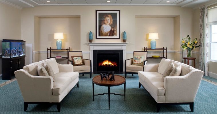 A well-decorated living room featuring a central fireplace and artwork, flanked by sofas and lamps.
