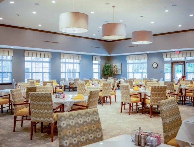 A spacious and well-lit dining area with multiple tables and chairs arranged neatly.