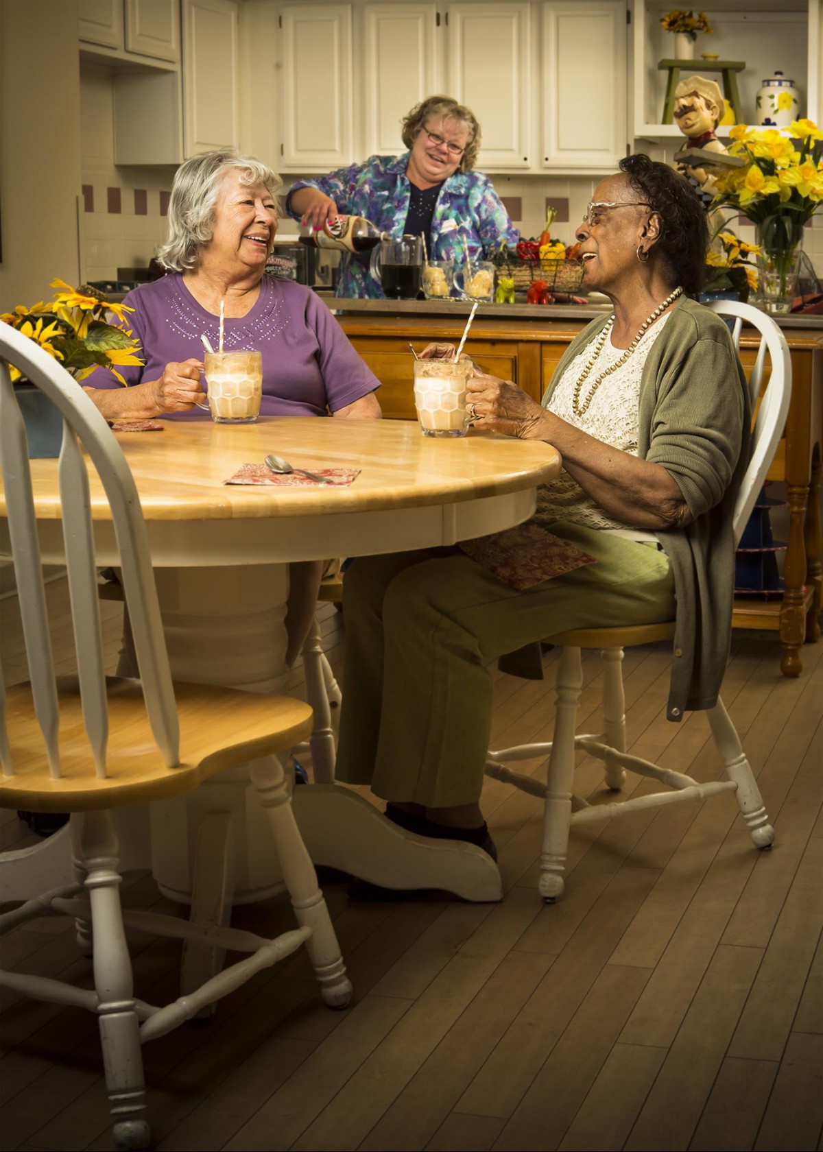 Two elderly women enjoying a conversation over coffee in a cozy kitchen setting.