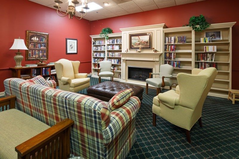 A cozy library room with a fireplace and comfortable seating area.