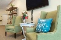 A cozy living room setup with green chairs, a decorative pillow, and a floral arrangement on a side table.