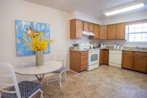A bright kitchen with wood cabinets, a dining table, and modern appliances.