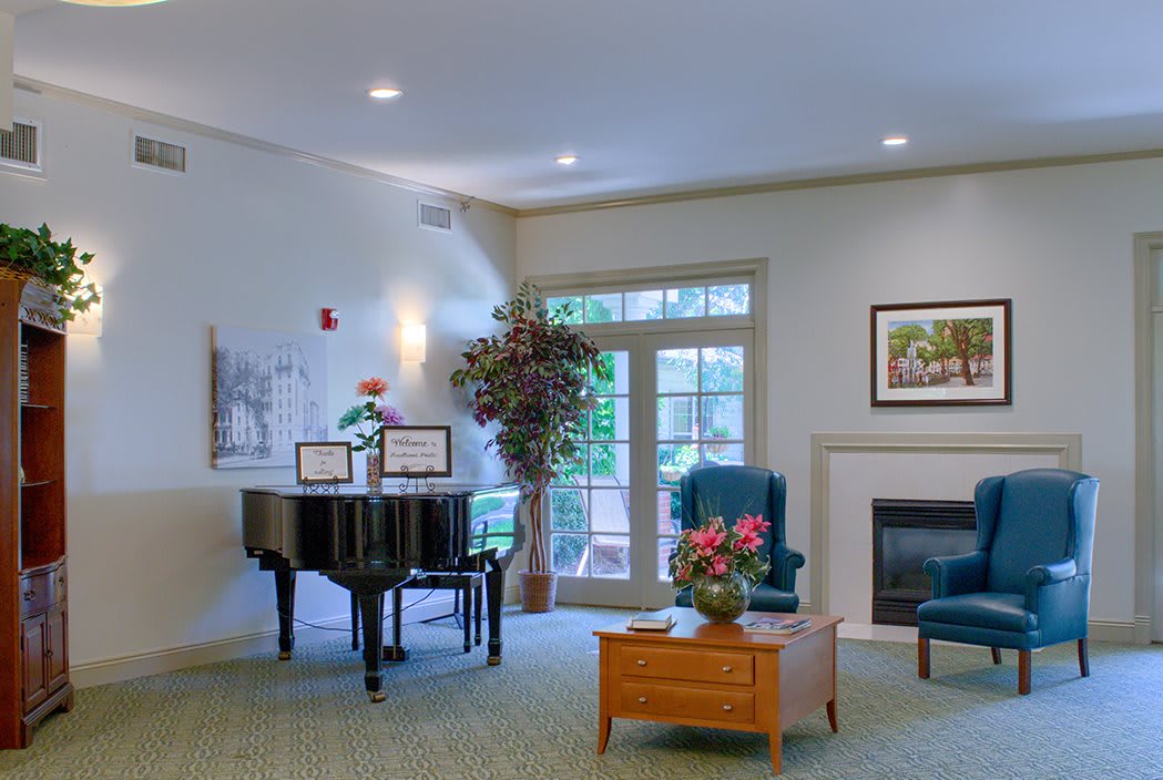 A cozy living room featuring a piano, comfortable seating, and a fireplace.
