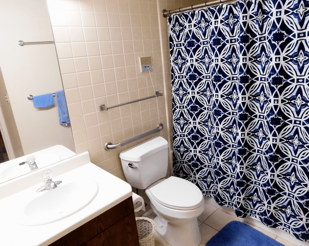 A clean bathroom with a blue geometric shower curtain and modern fixtures.