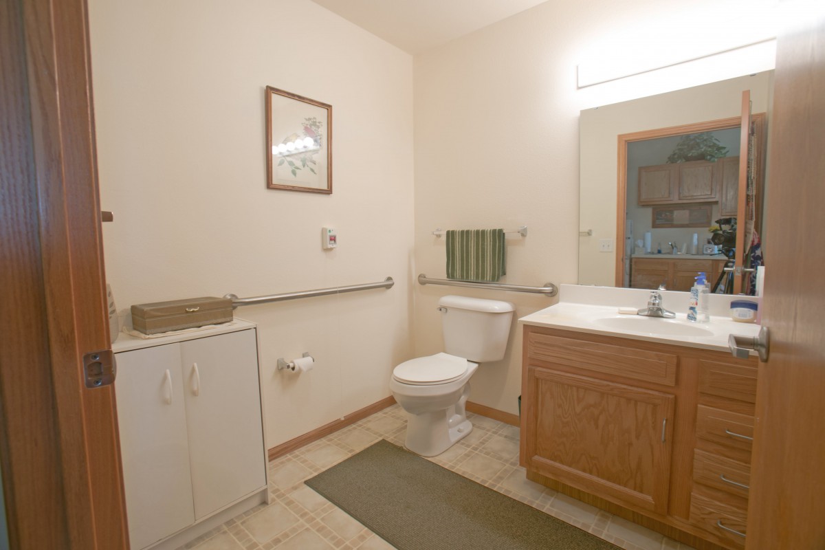 A simple and clean bathroom with a toilet, sink, mirror, and towel rack.