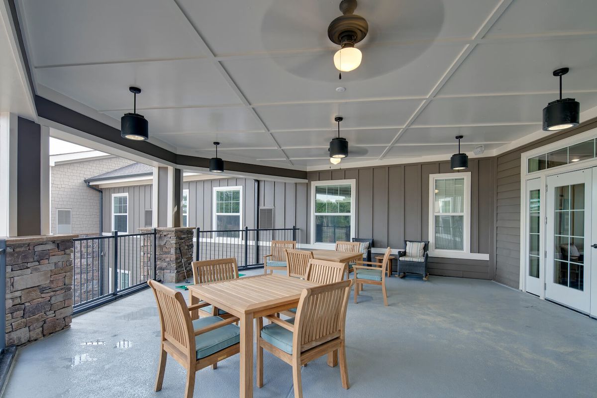 A covered patio area with wooden furniture and ceiling fans.