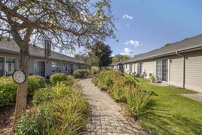 A peaceful garden with a stone pathway leading between buildings.