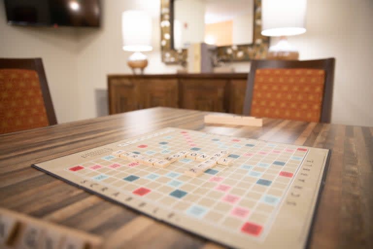 A Scrabble board sits ready for play on a dining table in a cozy room setting.