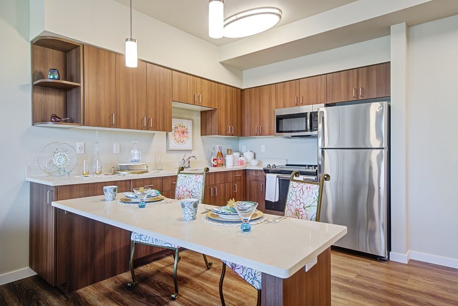 A modern kitchen with wooden cabinets, stainless steel appliances, and a dining table set for a meal.