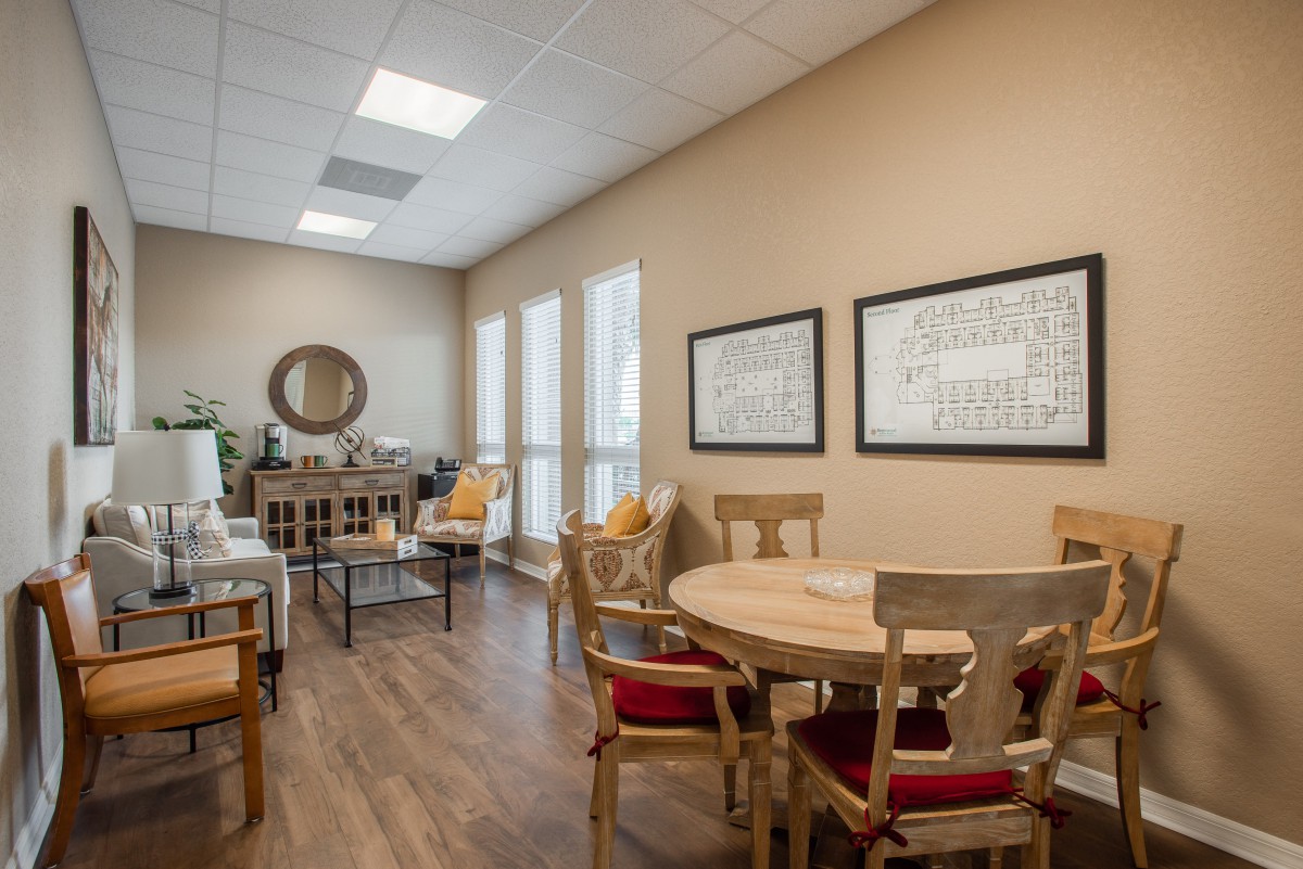 A cozy dining room with wooden floors, featuring a round table and chairs, adorned with wall art and a mirror.