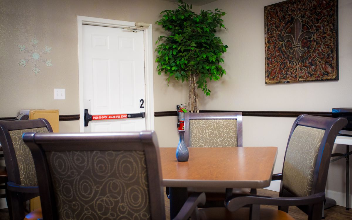 A small meeting room with a wooden table, upholstered chairs, and an indoor plant.