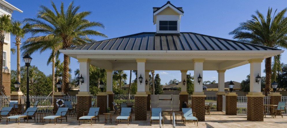 A poolside pavilion with lounge chairs and a roofed structure on a sunny day.