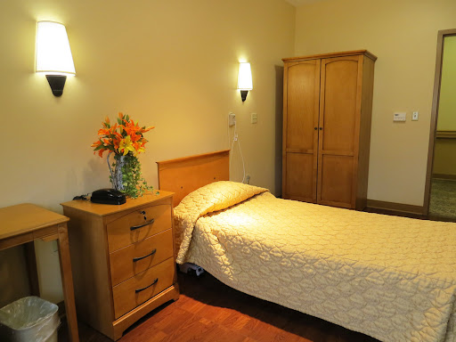 A cozy bedroom featuring a single bed, wooden furniture, and decorative flowers.