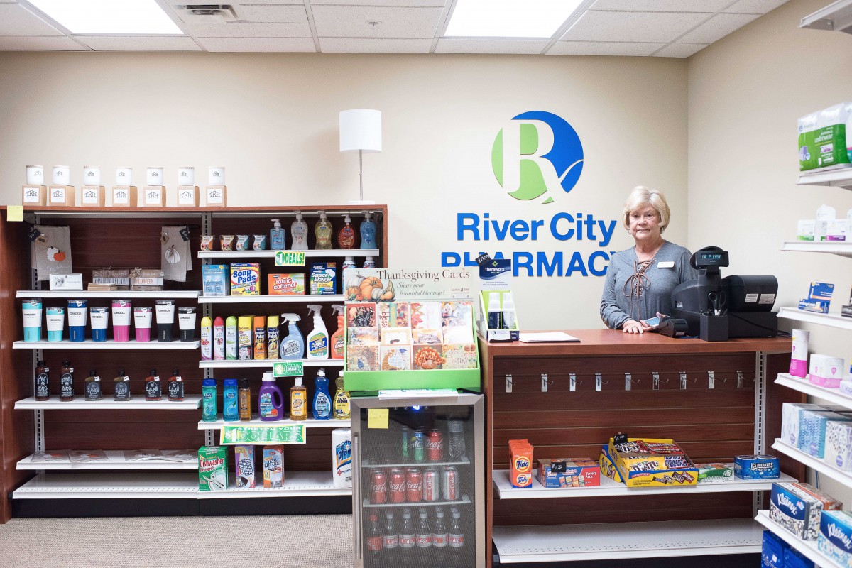 A pharmacy interior with a cashier behind the counter and various products on display.