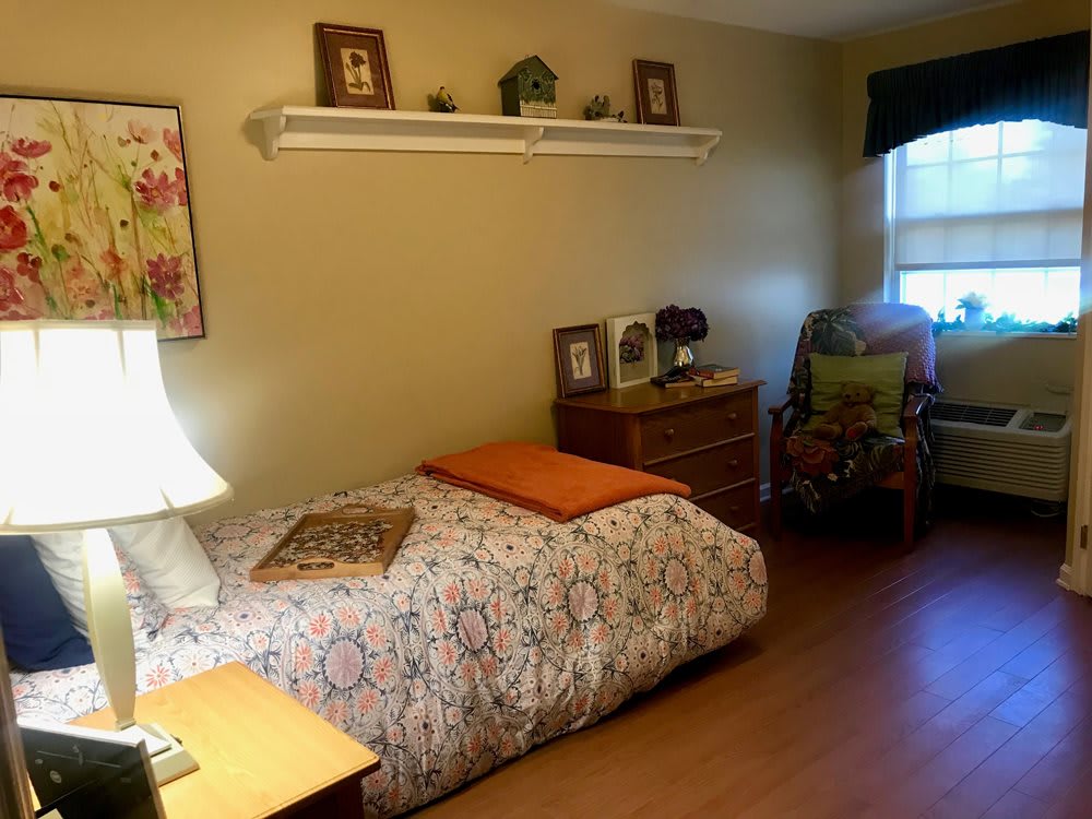 A cozy bedroom with a single bed, nightstand, and decorative items on the wall shelf.