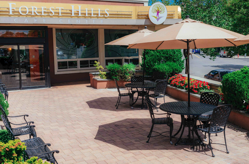 A charming outdoor seating area of a cafe featuring tables with umbrellas and vibrant flower beds.