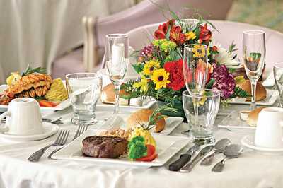 A beautifully set table featuring a steak dinner with elegant glassware and floral centerpiece.