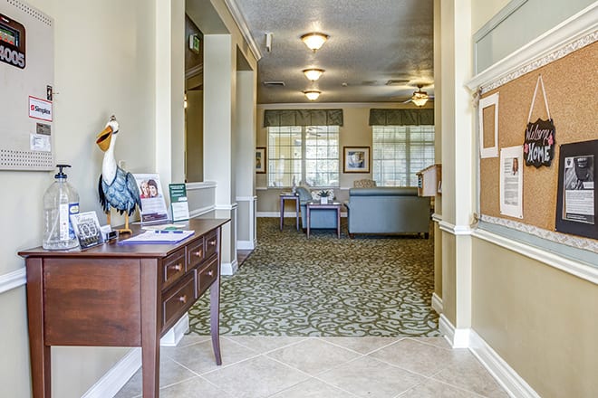 A well-lit hallway featuring furniture and decor, with a carpeted floor and ceiling lights.