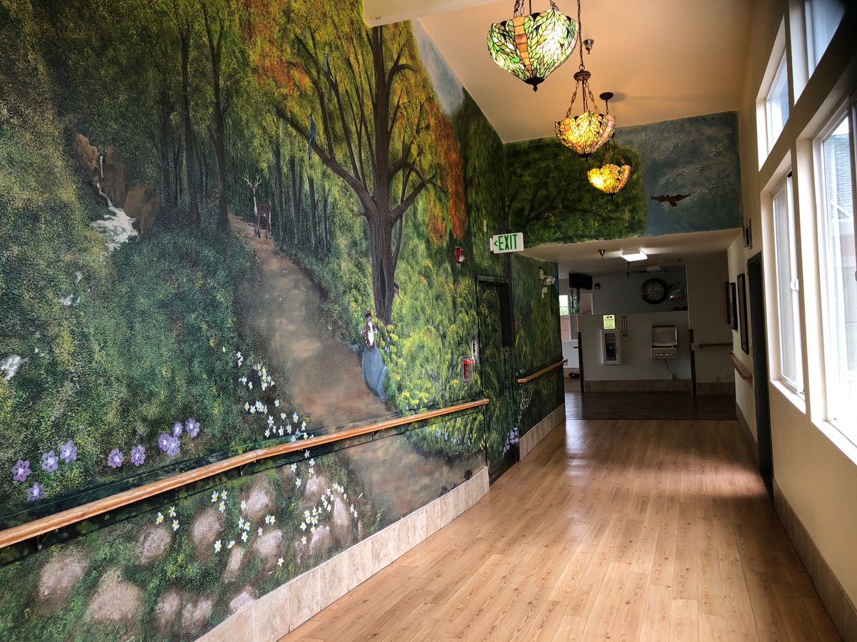 A hallway with a forest-themed mural and decorative lanterns.