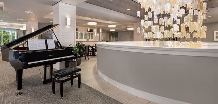 A modern hotel lobby featuring a grand piano and elegant chandeliers.