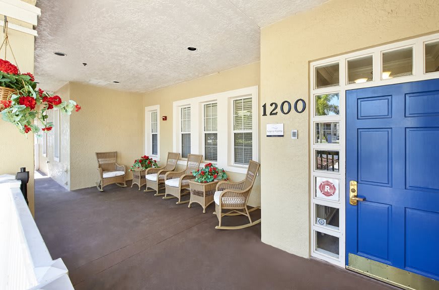 A cozy porch with wicker chairs and a blue front door, marked with the number 1200.