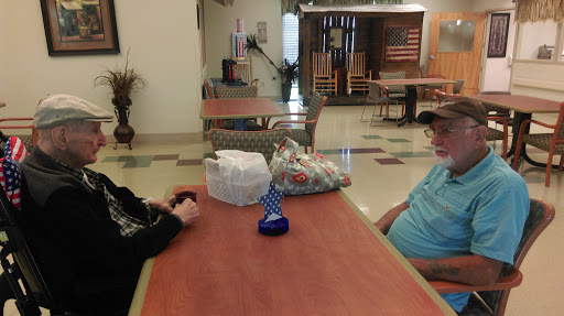 Two individuals sit at a table engaging in conversation in a communal space.