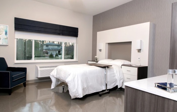 A modern, minimalist bedroom with a neatly made bed and large window.