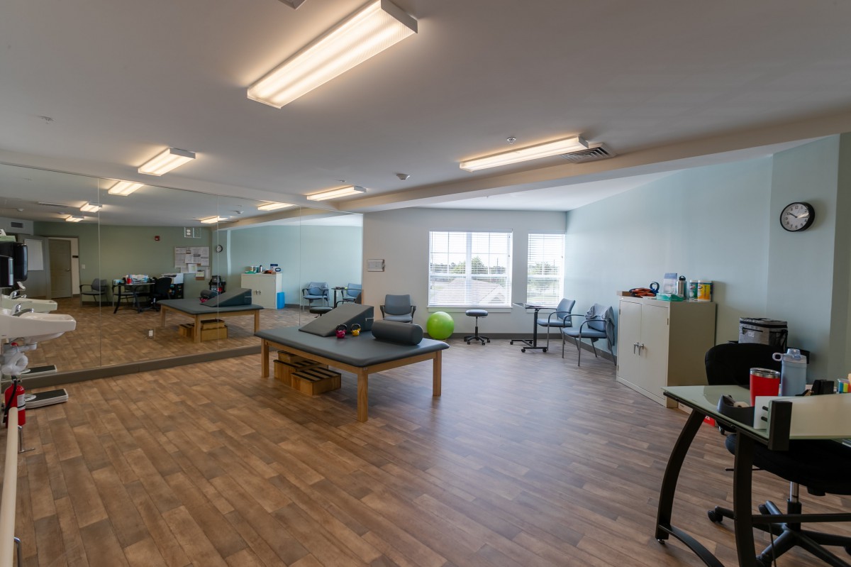 A spacious physical therapy clinic with treatment tables and exercise equipment.