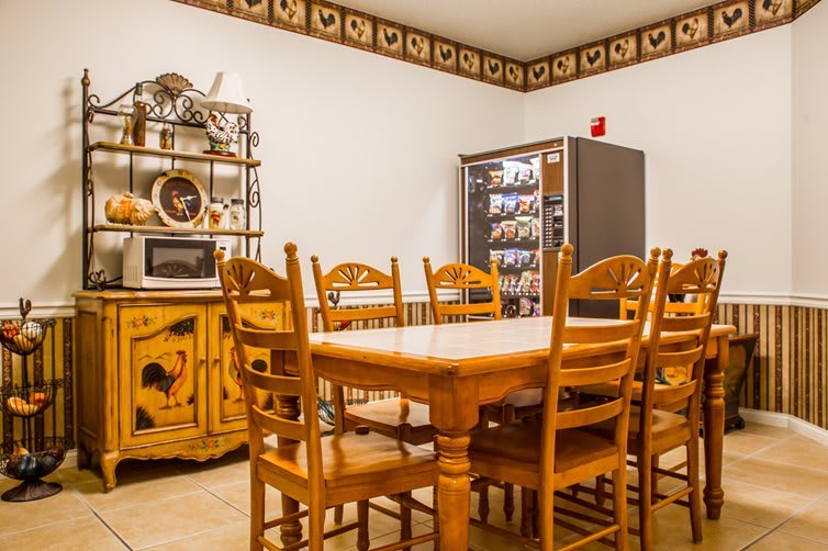 A cozy dining area featuring wooden furniture and a vending machine, complemented by country-style decor.