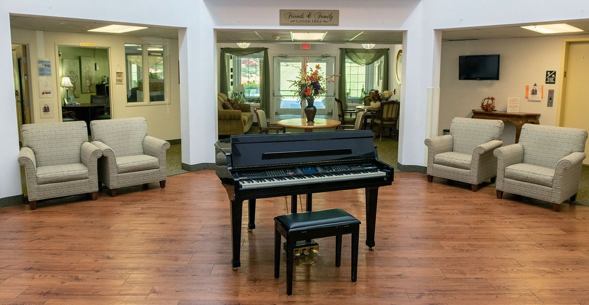 A black piano and bench in a lobby area with comfortable seating and decor.