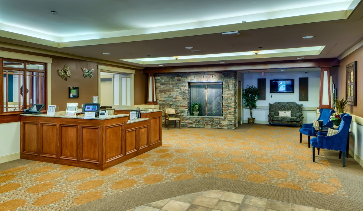 A spacious and well-lit lobby with a reception desk, stone wall, and decorative plants.
